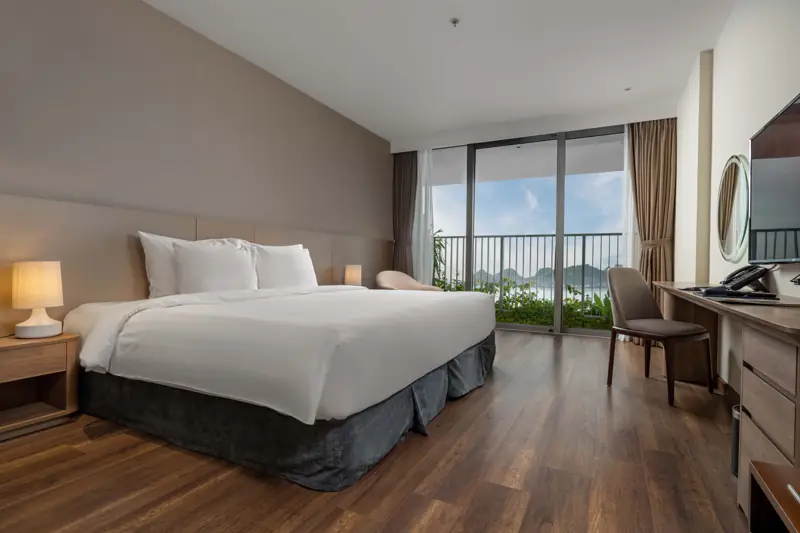 Phòng Deluxe Ocean View giường đôi lớn, sàn gỗ, cửa kính ra ban công nhìn vịnh