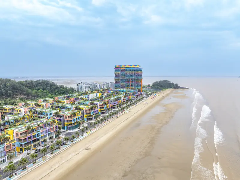 Bãi biển Hải Tiến dài và thoải nhìn từ trên cao, sóng trắng chạy dọc mép nước, xa xa là tòa khách sạn Flamingo Hải Tiến