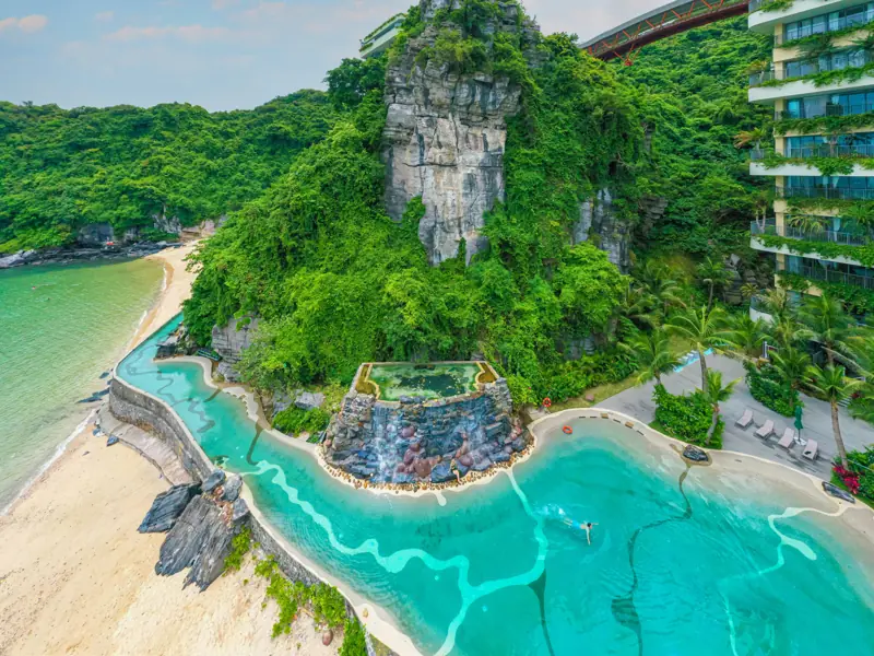 Bể bơi Charm Pool màu ngọc uốn quanh chân núi đá, sát bãi cát Cát Cò, nhìn từ trên cao
