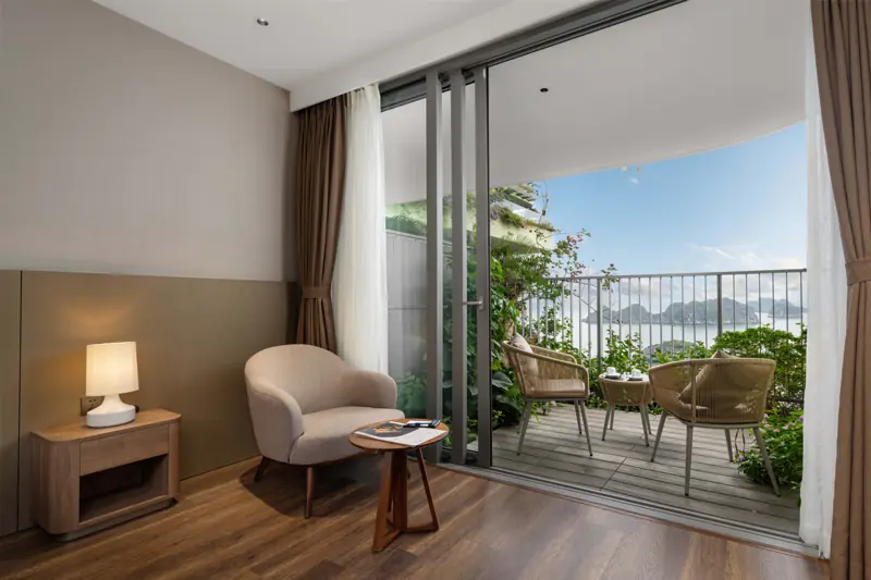 Góc phòng Premier Ocean View với ghế bành, bàn nhỏ và cửa kính mở ra ban công nhìn biển