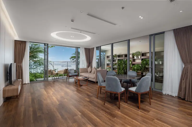 Phòng khách căn Residence 2 phòng ngủ với sofa, bàn ăn và vách kính lớn nhìn ra biển