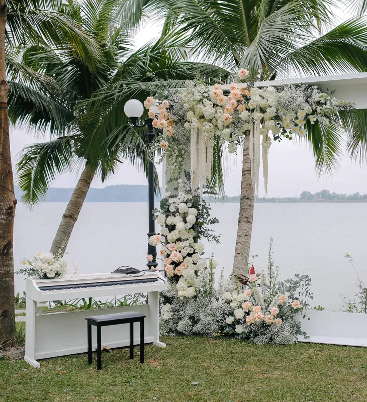 Cổng hoa trắng và hồng cạnh cây đàn piano trắng trên bãi cỏ ven hồ Đại Lải