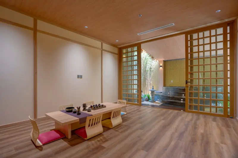 Phòng Washitsu kiểu Nhật sàn gỗ, bàn trà thấp và đệm ngồi, cửa lưới gỗ mở ra khu ngâm