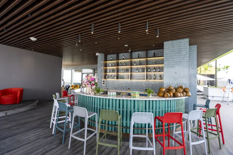 Quầy Skyline Bar tròn ốp gạch xanh với ghế cao nhiều màu cạnh bể vô cực tầng 21