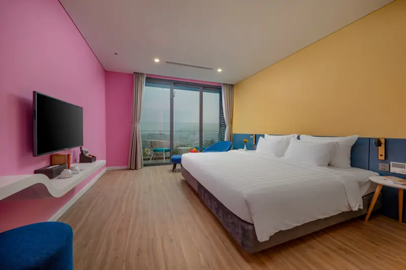 Phòng Deluxe Flamingo Hải Tiến với giường lớn, tường hồng và cửa kính lớn