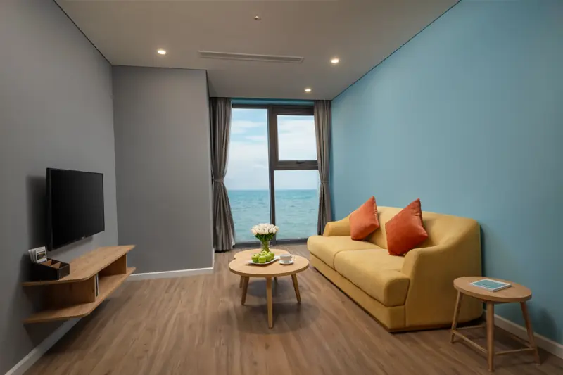 Phòng khách căn Premier Residence 02 phòng ngủ: sofa vàng, cửa kính nhìn ra biển