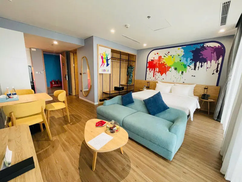 Phòng Premier có giường đôi, sofa xanh, bàn ăn nhỏ và tranh màu trên tường