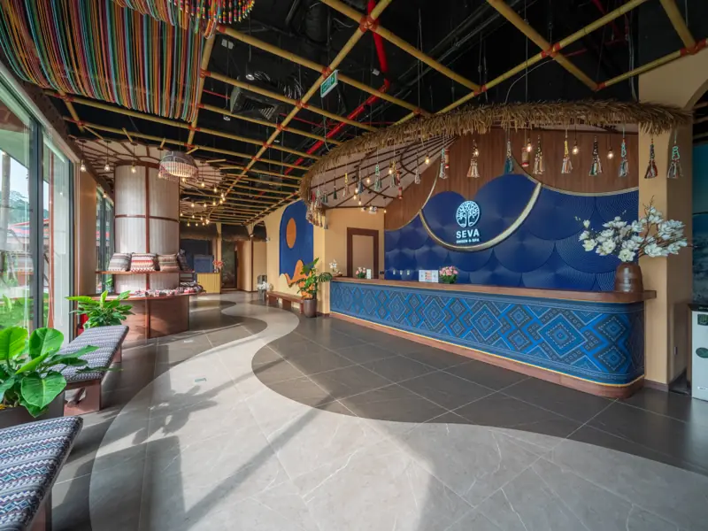 Quầy lễ tân SEVA Onsen & Spa ốp hoa văn xanh, cột tre đan và lối đi lát đá