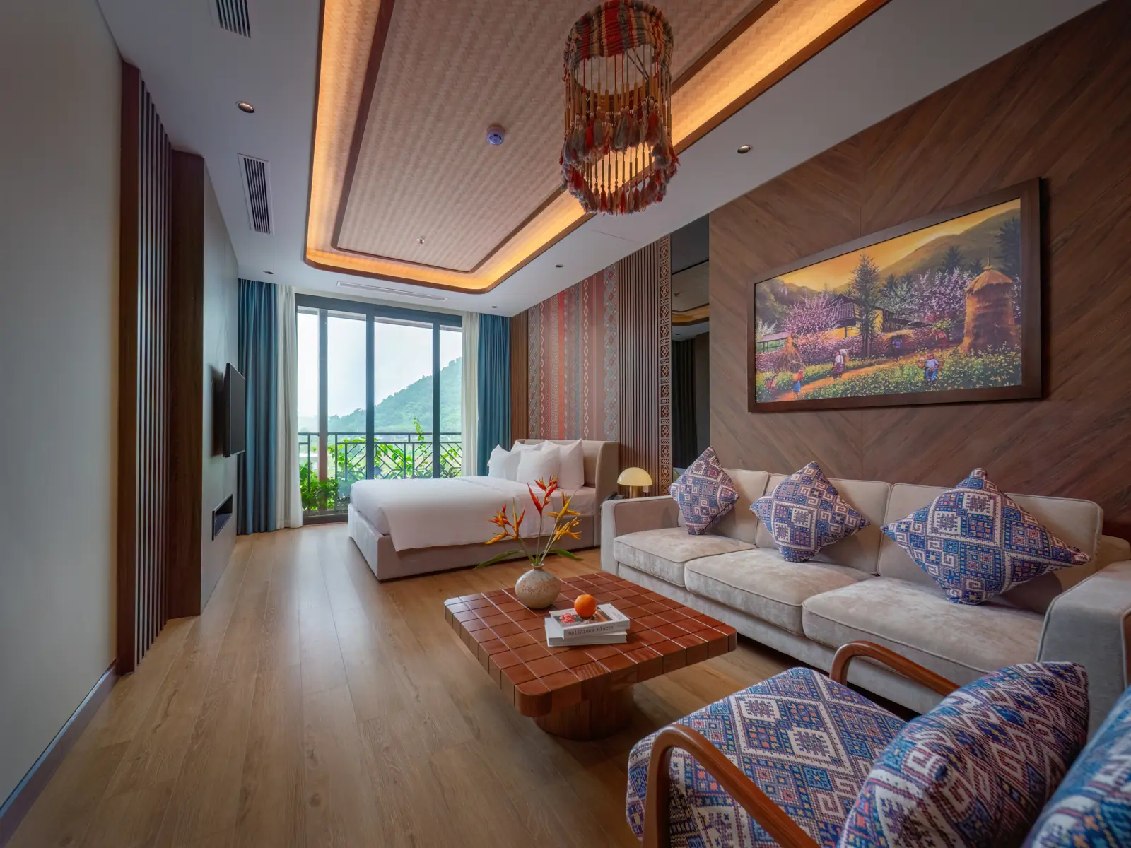 Phòng Deluxe Residence ở Flamingo Tân Trào: góc sofa họa tiết thổ cẩm, giường đôi và cửa kính nhìn ra núi