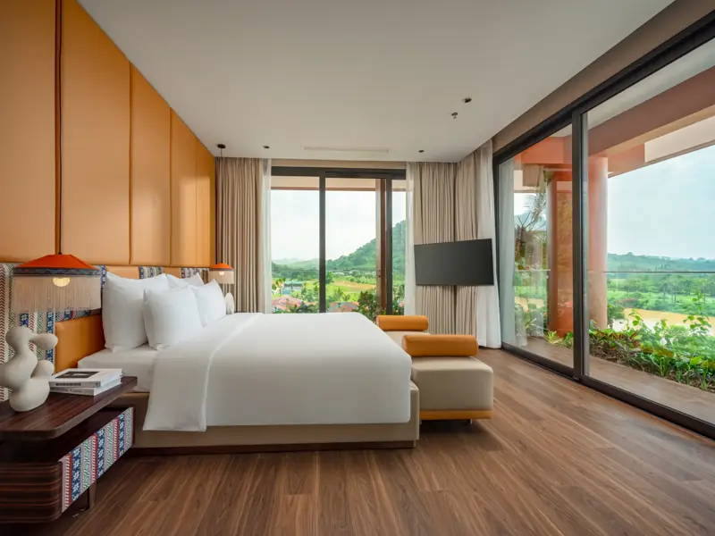 Phòng ngủ Presidential Suite: giường đôi, vách kính hai mặt nhìn ra núi và đồng