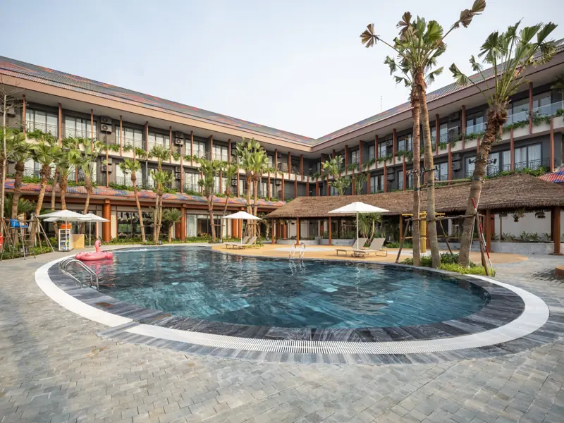 Hồ bơi ngoài trời giữa hai cánh tòa khách sạn Flamingo Tân Trào, có ô dù và ghế nằm