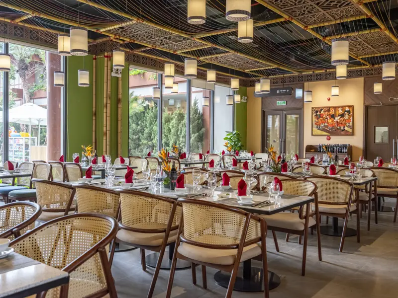 Nhà hàng Páo Dung Dining với bàn ghế mây, đèn lồng và cửa kính nhìn vườn